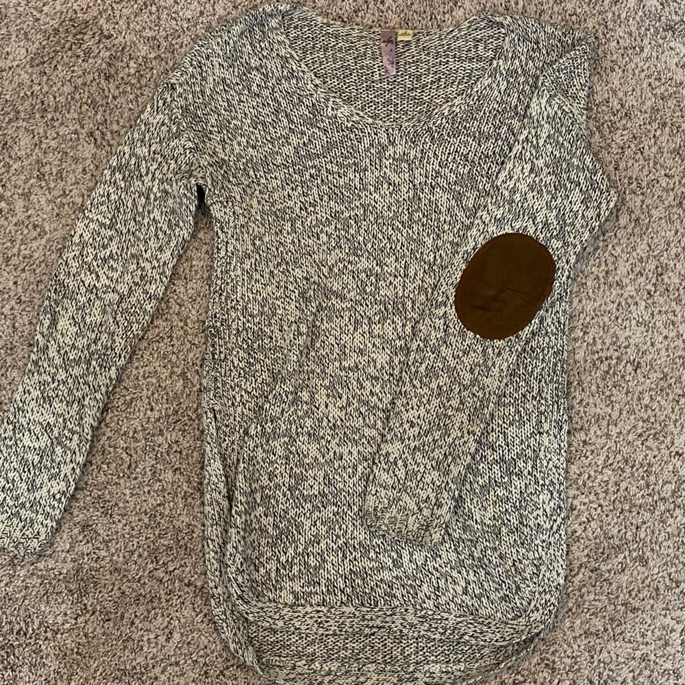 White and black knit sweater with brown suede elbow pads.